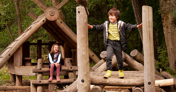 boy and girl playing on woodland play area